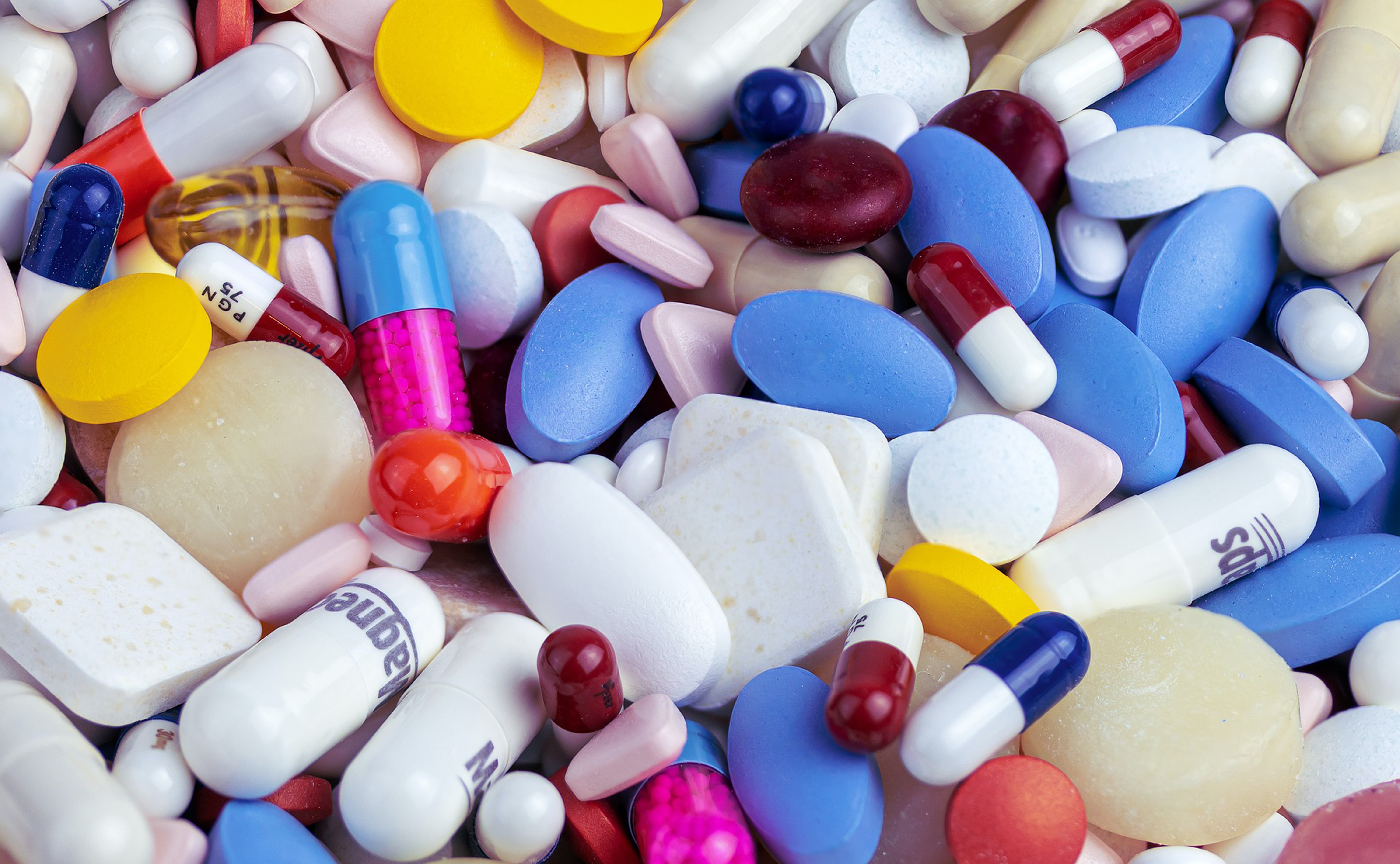 Photo-realistic image of a large pile of medicinal pills in various sizes, shapes, and colors.