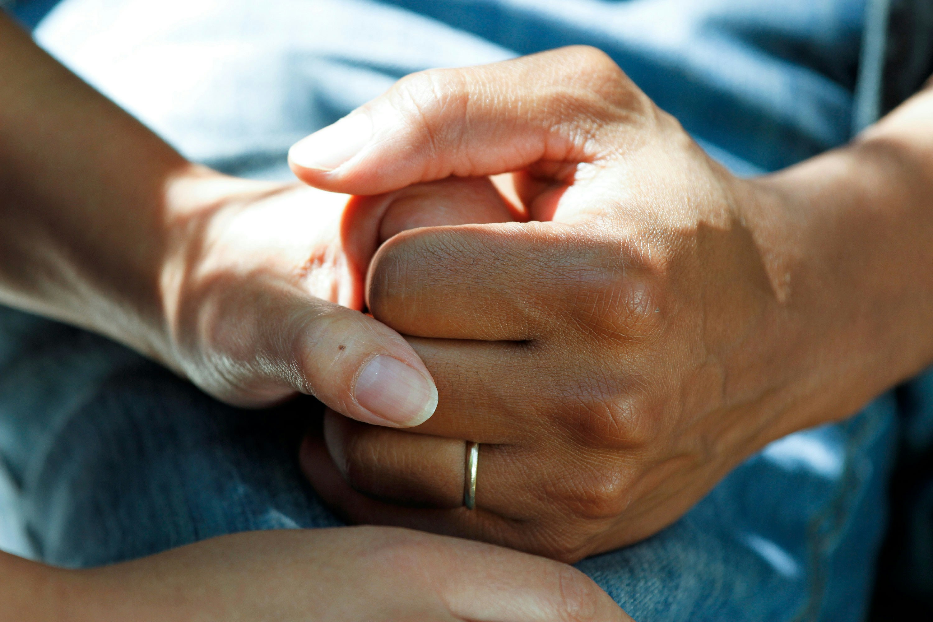 Photo by National Cancer Institute on Unsplash photo of two hands holding, one has a gold wedding band.